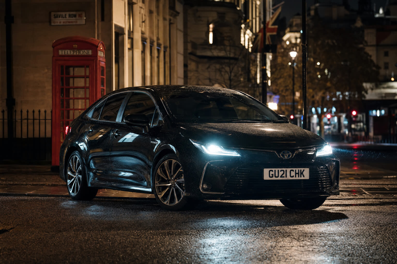 V Everyday black compact saloon parked at night on a London street